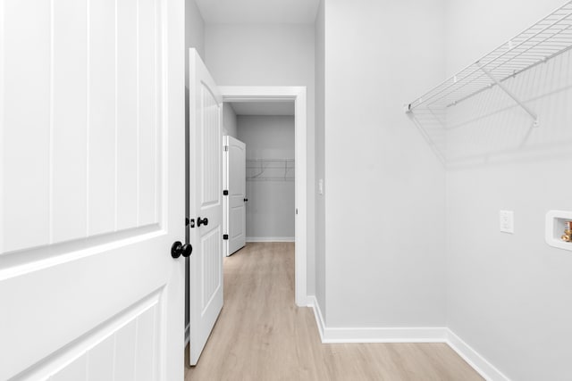 washroom with hookup for a washing machine, baseboards, and light wood finished floors