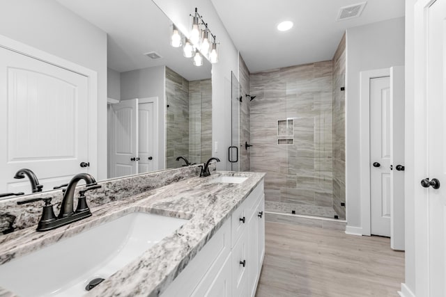 bathroom with an enclosed shower, vanity, and wood-type flooring