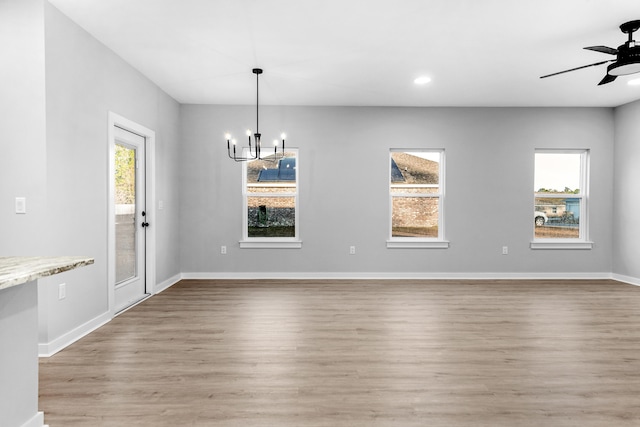 unfurnished dining area featuring ceiling fan with notable chandelier, plenty of natural light, and light hardwood / wood-style floors