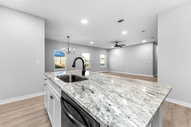 kitchen featuring black dishwasher, a center island with sink, visible vents, white cabinetry, and a sink