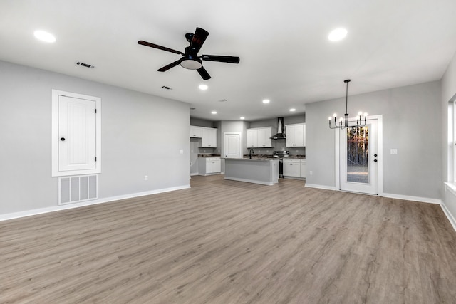 unfurnished living room featuring recessed lighting, visible vents, light wood-type flooring, baseboards, and ceiling fan with notable chandelier