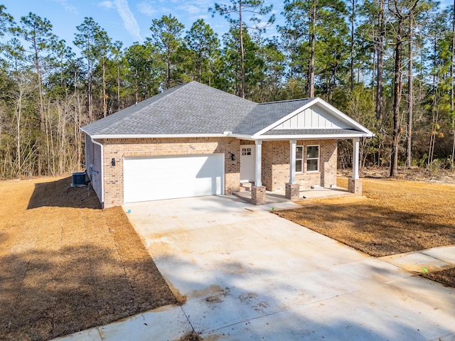 view of front of house with roof with shingles, brick siding, central air condition unit, concrete driveway, and a garage