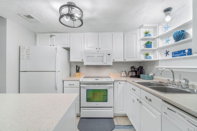 kitchen with sink, white appliances, light tile patterned floors, white cabinetry, and a textured ceiling