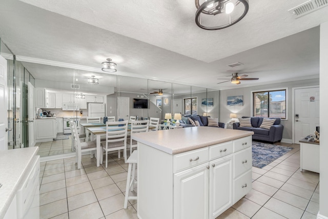 kitchen featuring white cabinetry, light tile patterned floors, white appliances, and a kitchen island