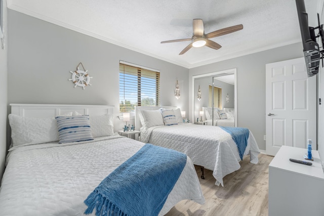 bedroom featuring crown molding, light hardwood / wood-style flooring, a textured ceiling, a closet, and ceiling fan