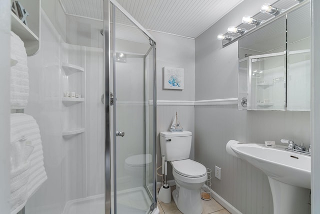 bathroom with sink, a shower with shower door, tile patterned floors, and toilet