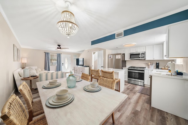 dining space featuring sink, crown molding, ceiling fan with notable chandelier, and light hardwood / wood-style floors