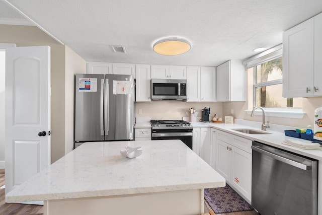 kitchen featuring appliances with stainless steel finishes, sink, a kitchen island, and white cabinets