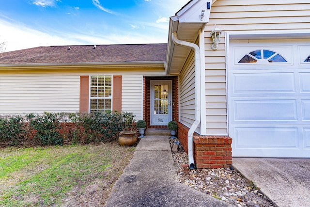 entrance to property with a garage and a shingled roof