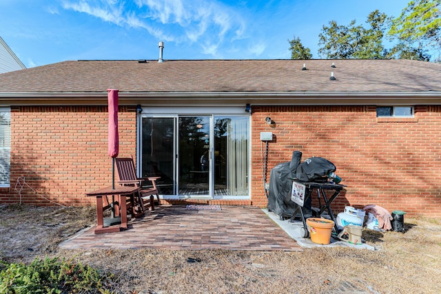 back of house featuring brick siding, roof with shingles, and a patio area