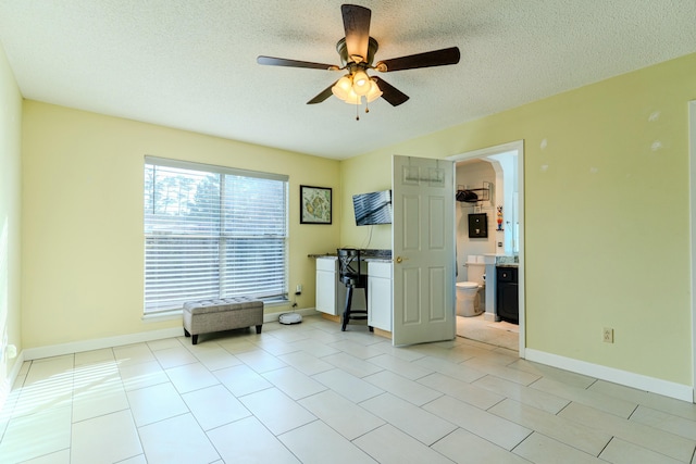 interior space with baseboards, a ceiling fan, and a textured ceiling