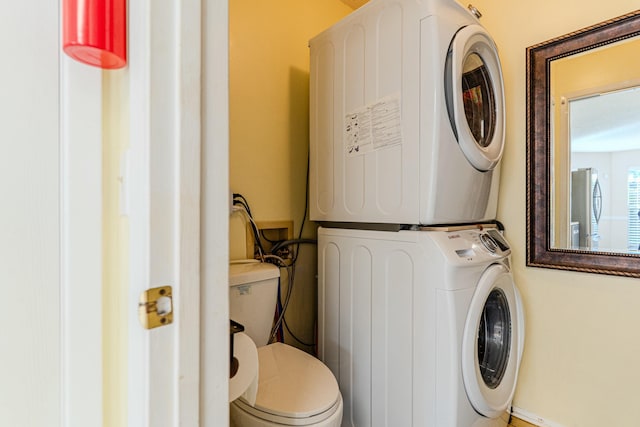 laundry area with laundry area, baseboards, and stacked washing maching and dryer