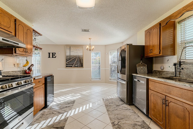 kitchen featuring appliances with stainless steel finishes, brown cabinets, hanging light fixtures, light countertops, and light tile patterned flooring