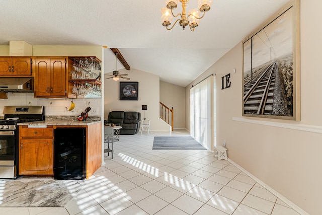 kitchen featuring beverage cooler, brown cabinetry, gas range, light countertops, and under cabinet range hood