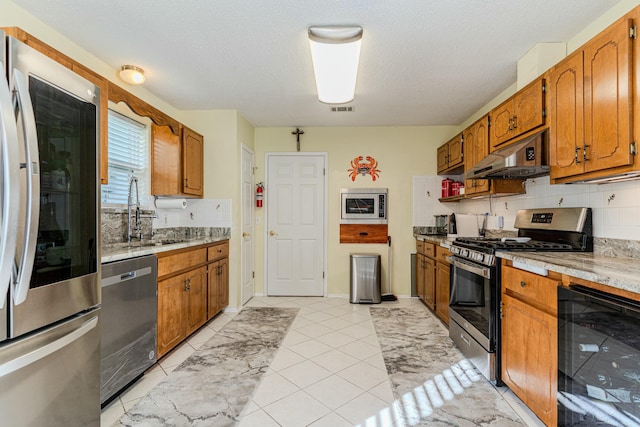 kitchen featuring under cabinet range hood, beverage cooler, stainless steel appliances, a sink, and light countertops