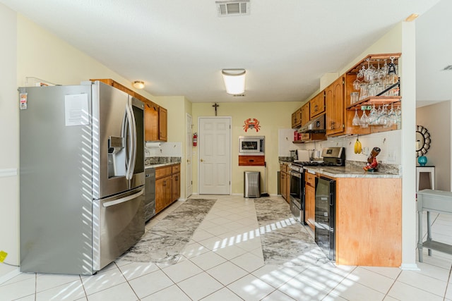 kitchen featuring beverage cooler, visible vents, light countertops, appliances with stainless steel finishes, and brown cabinetry