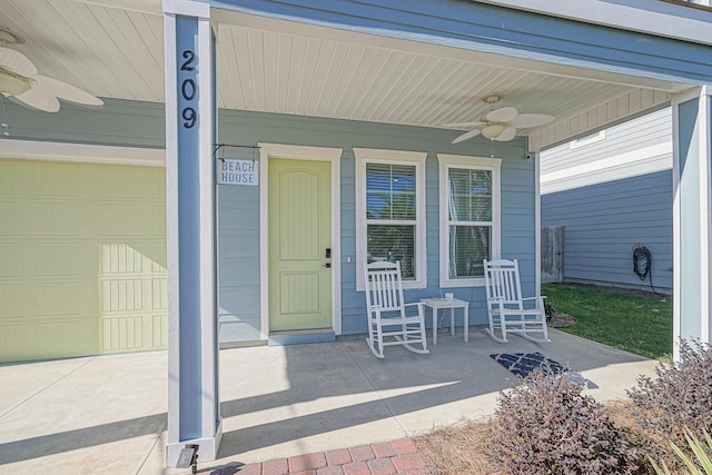 entrance to property with a garage, ceiling fan, and covered porch