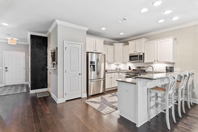 kitchen featuring white cabinetry, dark stone counters, a kitchen breakfast bar, kitchen peninsula, and stainless steel appliances