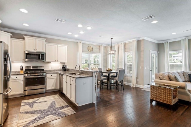 kitchen with hanging light fixtures, white cabinetry, appliances with stainless steel finishes, and kitchen peninsula