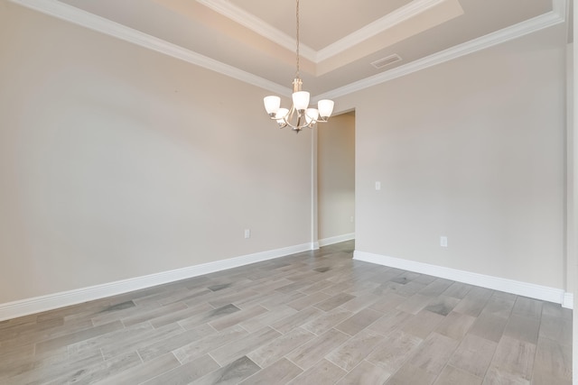 spare room with a notable chandelier, ornamental molding, a raised ceiling, and light wood-type flooring