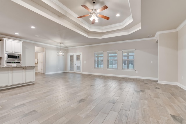 unfurnished living room with a raised ceiling, ceiling fan, crown molding, and light hardwood / wood-style floors