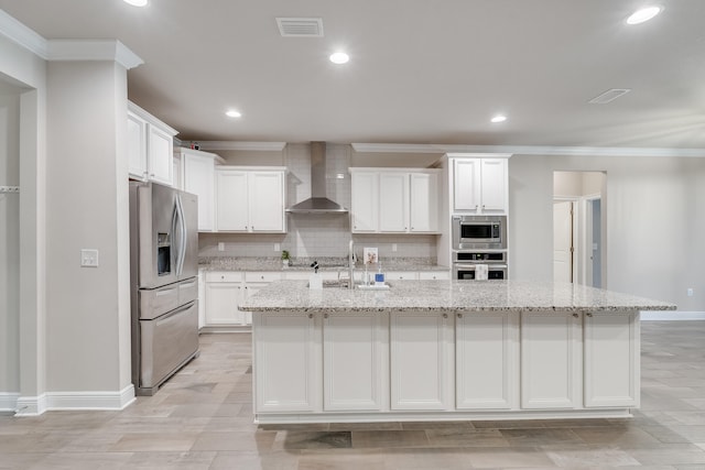 kitchen featuring white cabinetry, wall chimney range hood, stainless steel appliances, and a center island with sink