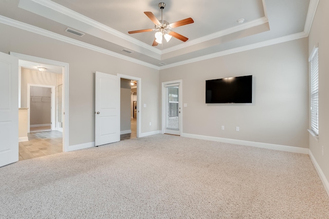 unfurnished bedroom featuring light carpet, crown molding, and a raised ceiling