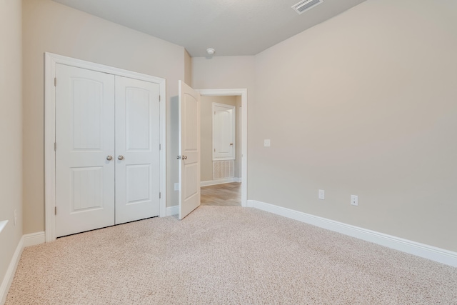 unfurnished bedroom with a closet and light carpet