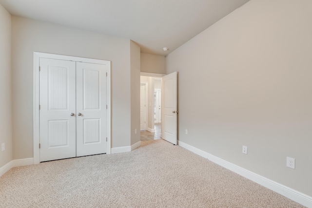 unfurnished bedroom with light carpet and a closet