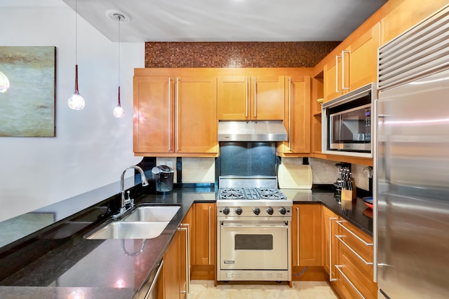 kitchen featuring sink, dark stone countertops, hanging light fixtures, backsplash, and premium appliances