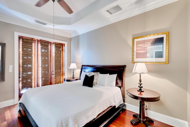 bedroom with hardwood / wood-style floors, crown molding, a raised ceiling, and ceiling fan