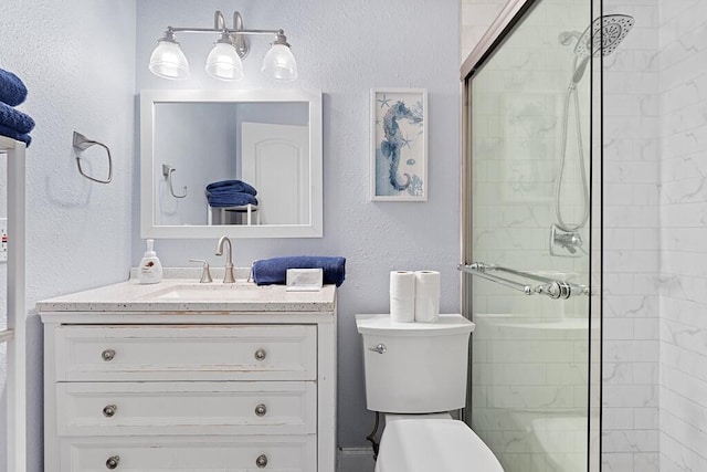 bathroom with walk in shower, vanity, and toilet