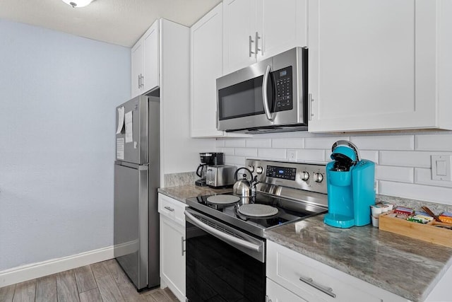 kitchen featuring white cabinetry, backsplash, stainless steel appliances, and light hardwood / wood-style floors