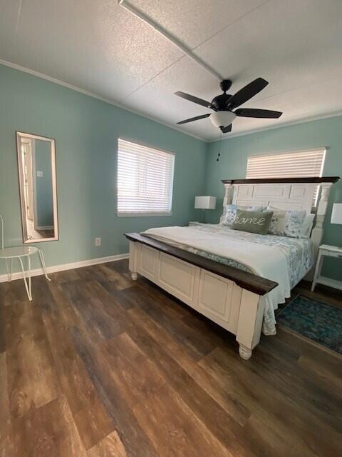 bedroom featuring dark wood-type flooring, ornamental molding, and ceiling fan