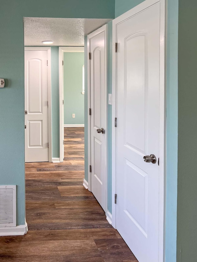 corridor with dark wood-type flooring and a textured ceiling