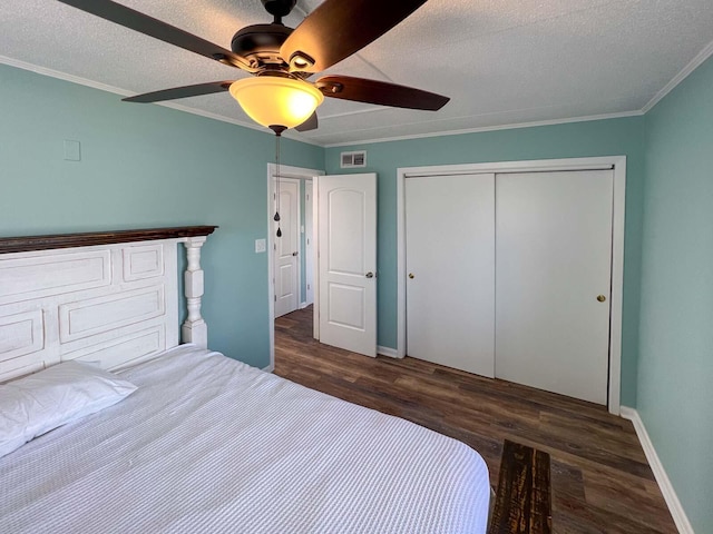 unfurnished bedroom featuring ceiling fan, crown molding, dark wood-type flooring, a textured ceiling, and a closet