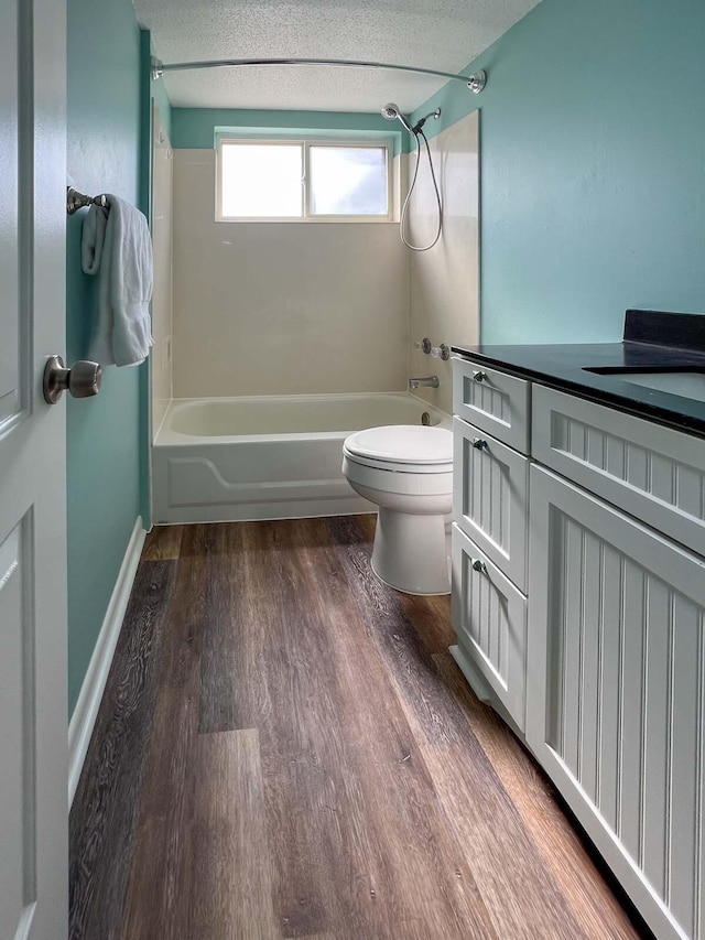 full bathroom with hardwood / wood-style floors, toilet, bathing tub / shower combination, and a textured ceiling