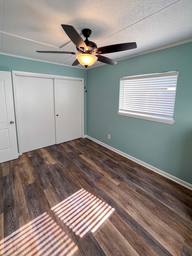 unfurnished bedroom with ceiling fan, dark wood-type flooring, a textured ceiling, and a closet