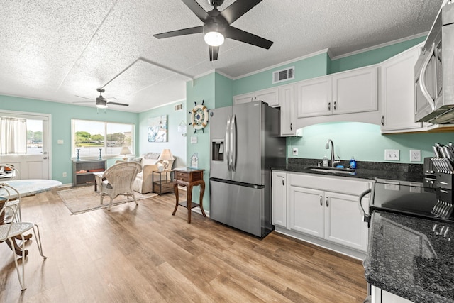 kitchen featuring stainless steel appliances, ceiling fan, a sink, open floor plan, and a textured ceiling