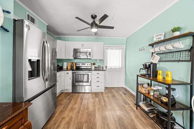 kitchen with stainless steel appliances, ceiling fan, a textured ceiling, dark countertops, and white cabinetry