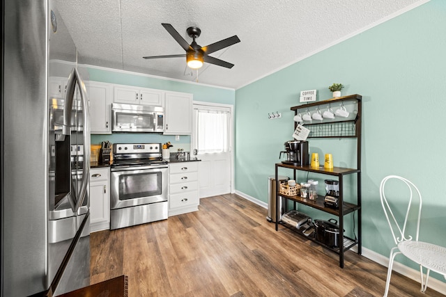 kitchen with appliances with stainless steel finishes, dark countertops, a textured ceiling, ceiling fan, and white cabinetry