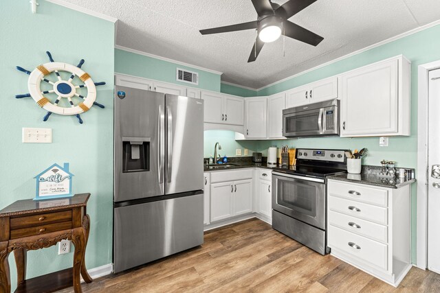 kitchen featuring appliances with stainless steel finishes, dark countertops, a sink, a textured ceiling, and ceiling fan