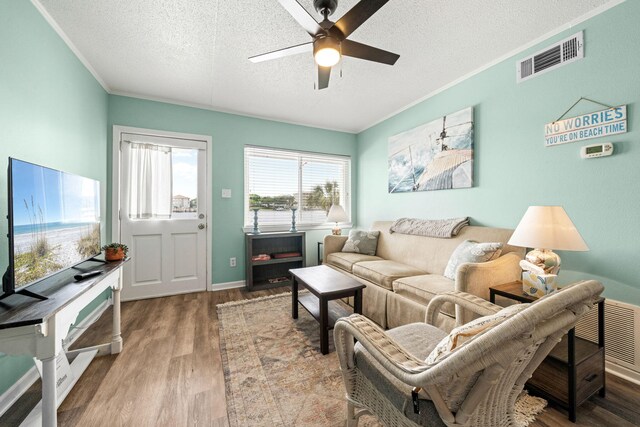 living area featuring a textured ceiling, a ceiling fan, wood finished floors, and ornamental molding