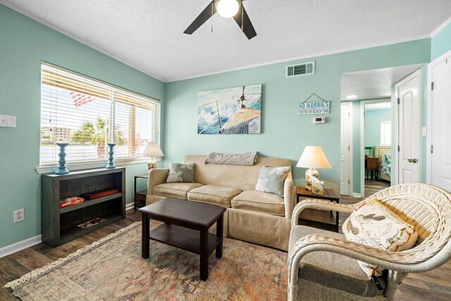 living area with ceiling fan, wood finished floors, a textured ceiling, plenty of natural light, and baseboards