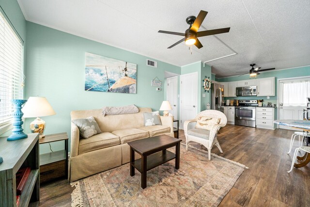 living area with a ceiling fan, dark wood-type flooring, and a textured ceiling