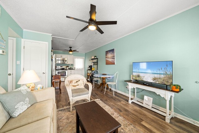living area with ceiling fan, wood finished floors, a textured ceiling, ornamental molding, and baseboards