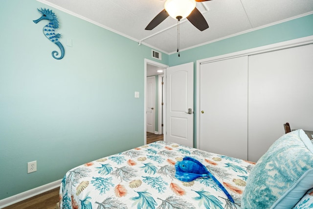 bedroom with dark wood-style flooring, ornamental molding, baseboards, a closet, and a ceiling fan