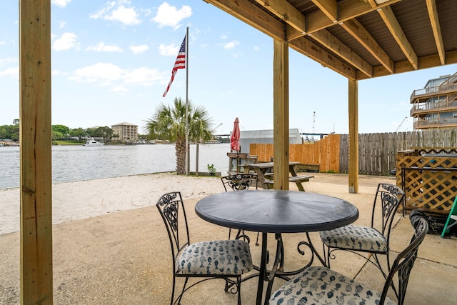 view of patio / terrace featuring a water view and fence