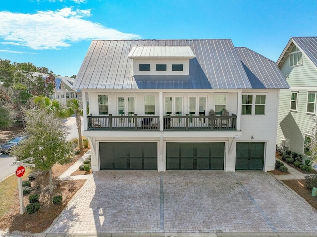 view of front of home featuring an attached garage, a balcony, and decorative driveway