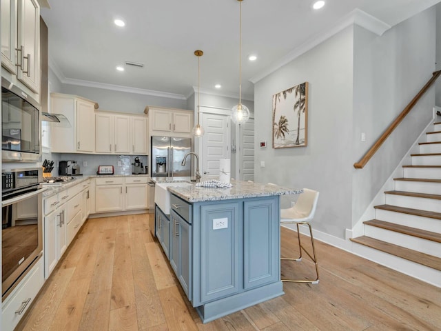 kitchen featuring light stone counters, a breakfast bar, decorative light fixtures, a center island with sink, and appliances with stainless steel finishes